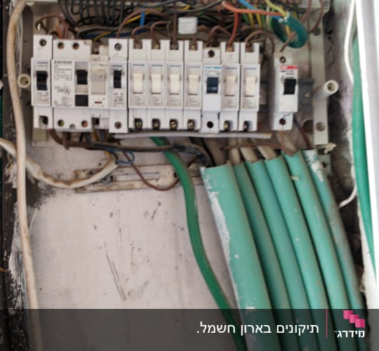 לוח חשמל עם מפסקים וחוטים חשמליים ירוקים